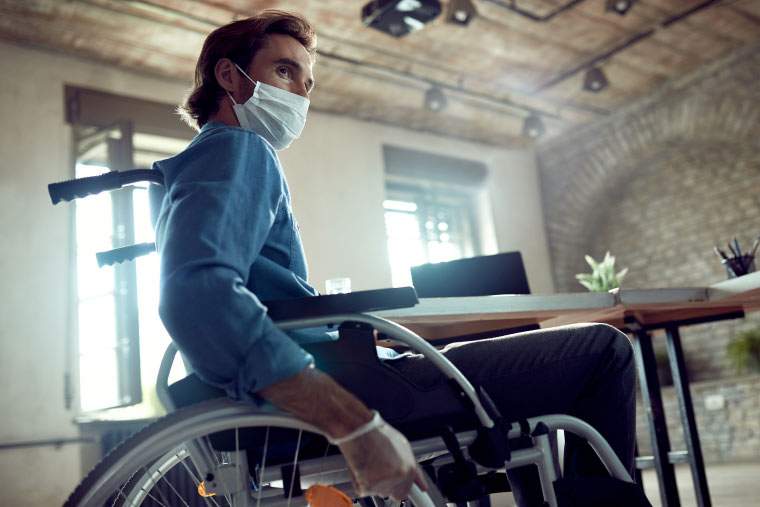 A man in a wheelchair wearing a medical mask